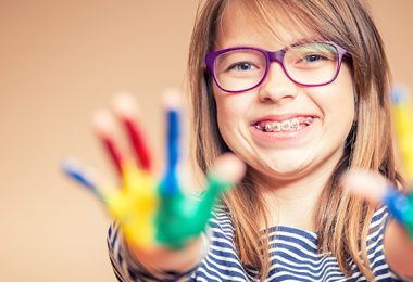 Mädchen mit Zahnspange spielt mit Farben