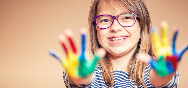 Mädchen mit Zahnspange spielt mit Farben